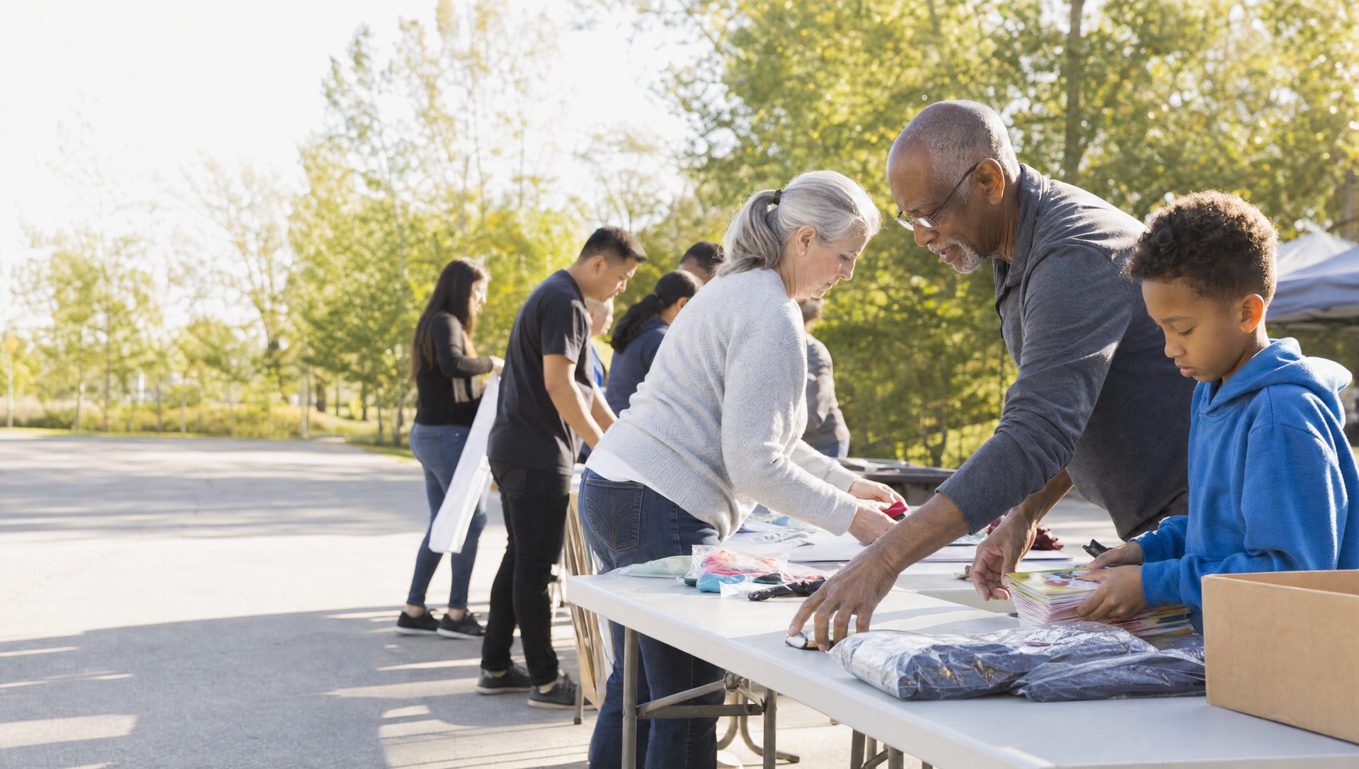 Volunteers of all ages sorting donated goods together at an outdoor community table